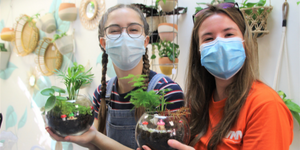 Two students smile while holding their plants.